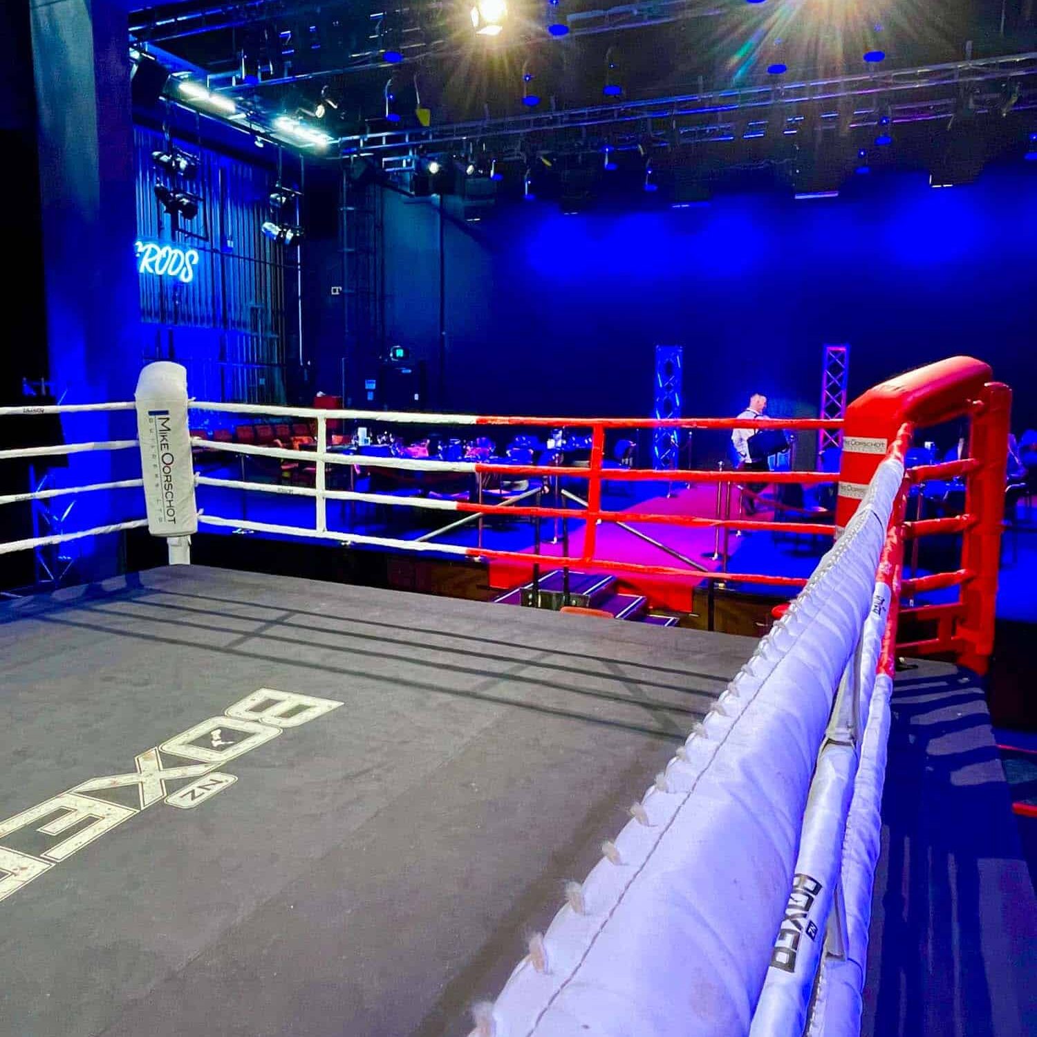 A boxing ring in an arena with blue lights.