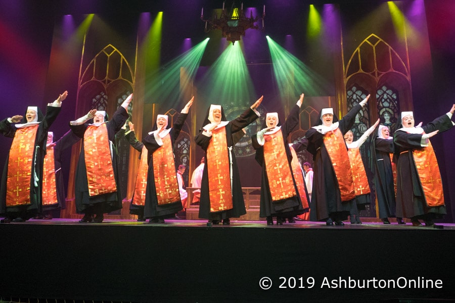 A group of nuns in robes on stage.
