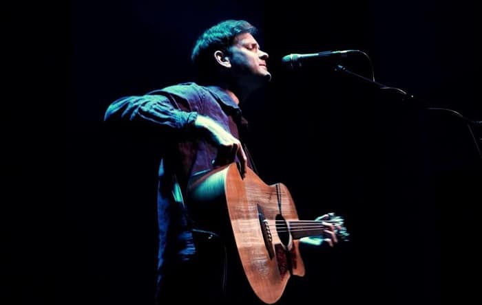 A man playing guitar and singing into a microphone.